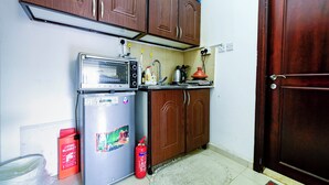 Une cuisine de taille réduite, dotée de meubles en bois, d’un réfrigérateur, d’un four à micro-ondes et d’une cuisinière.