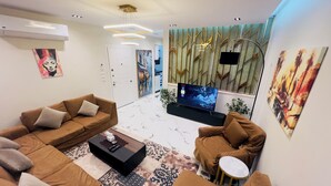 Una sala de estar moderna con un conjunto de sofá, una mesa de centro, un televisor y decoración en la pared.