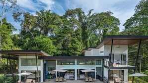 A modern house with a swimming pool, outdoor seating, and a large glass door leading to a patio. - Stunning 4-bedroom villa with infinity pool, 15 min. from Dominical (Uvita)