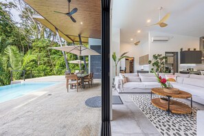 Un espacio de estar moderno con piscina, comedor y cocina.