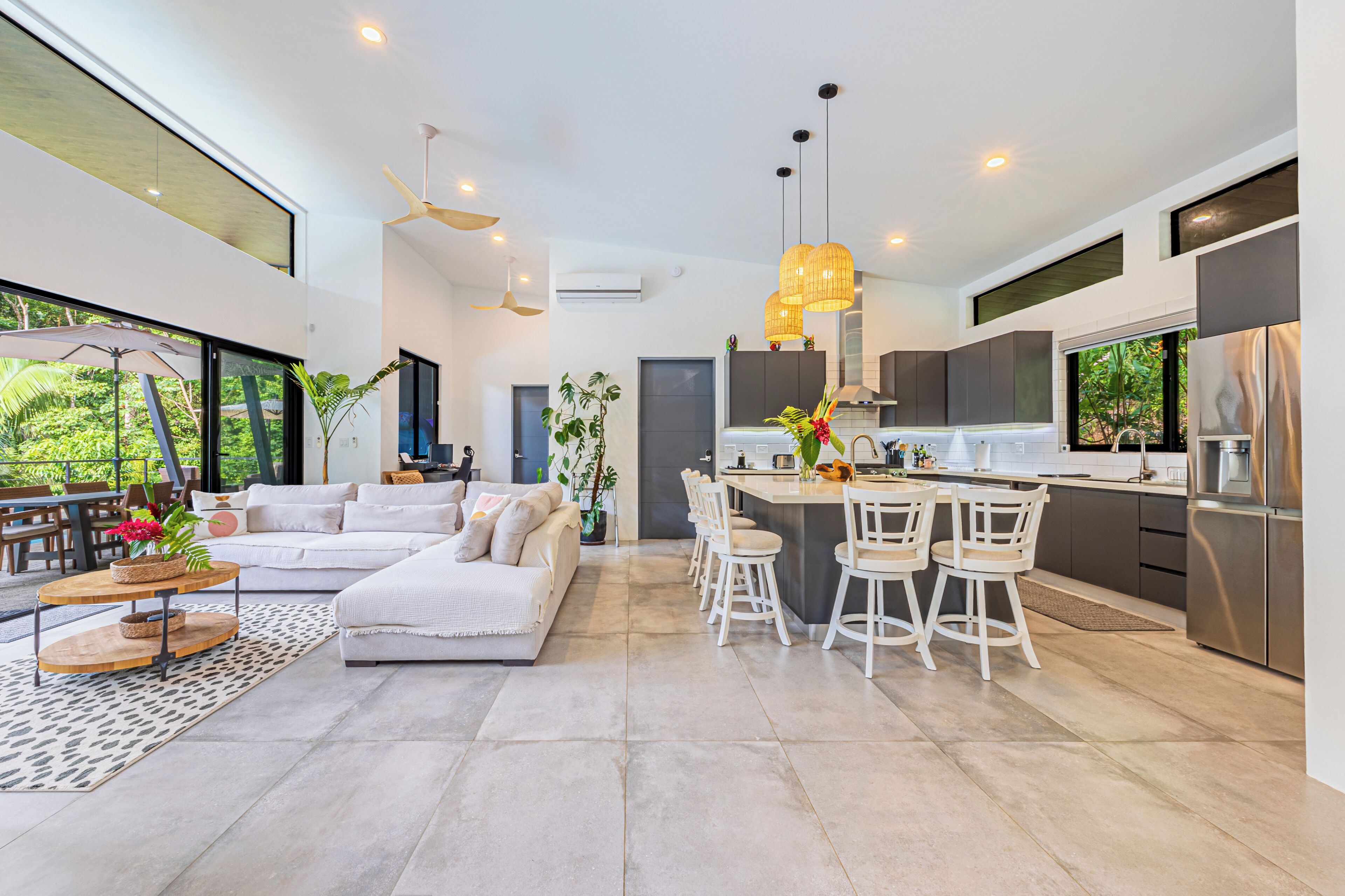 Een moderne keuken met een centraal eiland, witte barstoelen en een eethoek.