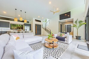 Una sala de estar moderna con sofá, mesa de centro y una escalera que lleva a un nivel superior.