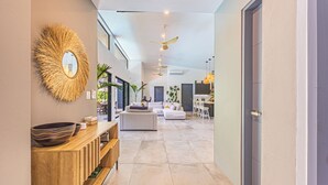 A modern interior with a wooden console, a large mirror, and a seating area with a sofa and chairs. - Stunning 4-bedroom villa with infinity pool, 15 min. from Dominical (Uvita)