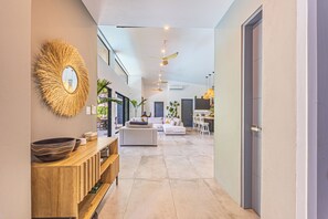 Un intérieur moderne avec une console en bois, un grand miroir et un espace salon comprenant un canapé et des fauteuils.