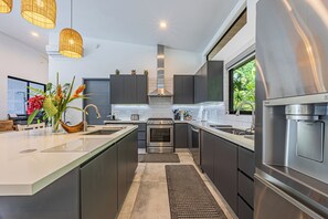 Una cocina moderna con una isla central, electrodomésticos de acero inoxidable y vistas a zonas verdes.