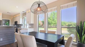A modern kitchen with a dining area, large windows, and a hanging light fixture. - 4BR Frisco Escape / Pool + Theater / Sleeps 10 / Spacious (Frisco)