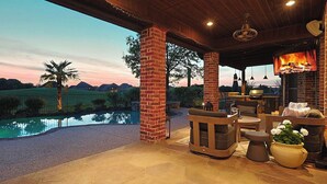 A covered outdoor area with a pool, seating, and a fireplace. - 4BR Frisco Escape / Pool + Theater / Sleeps 10 / Spacious (Frisco)