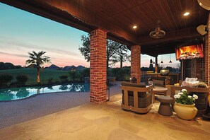 Ein überdachter Außenbereich mit Pool, Sitzgelegenheiten und Kamin.