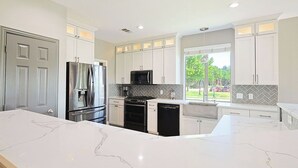 A modern kitchen with white cabinets, stainless steel appliances, and a marble countertop. - 4BR Frisco Escape / Pool + Theater / Sleeps 10 / Spacious (Frisco)