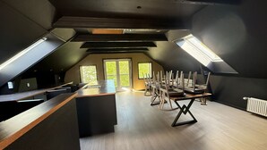A modern loft with a kitchen area, a dining table with chairs, and skylights. - Four Seasons - Carnival Summer Lounge (Aalborg)