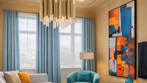 A modern living room with a sofa, armchair, coffee table, and a large abstract painting on the wall. - Four Seasons - Carnival Summer Lounge (Aalborg)