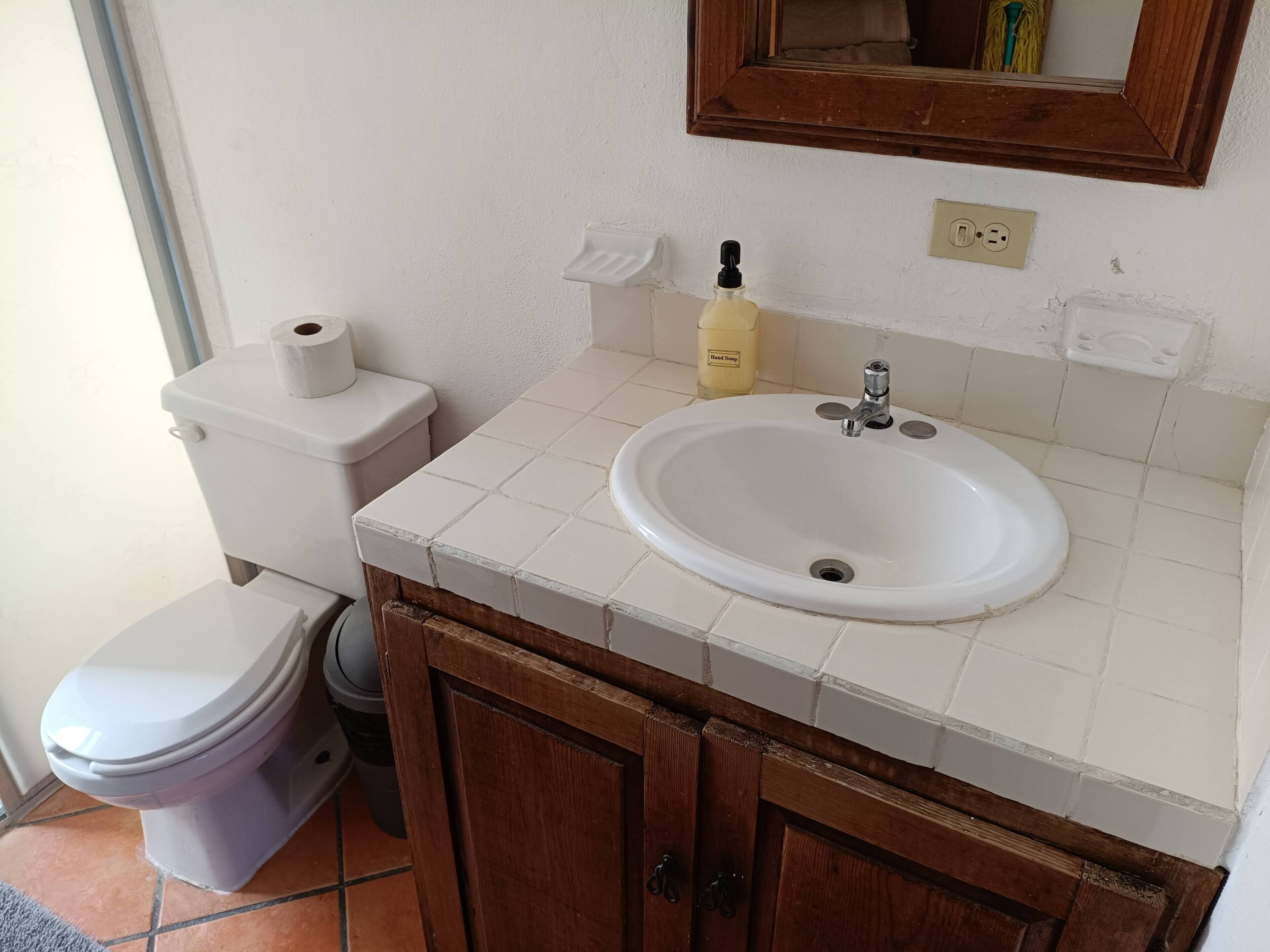 A bathroom with a toilet, sink, and mirror.