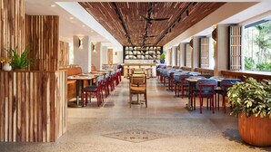 A spacious restaurant with long tables, wooden paneling, and a central bar area. - King | Wayfinder Waikiki | Waikiki Beach, Saltwater Pool, Local Art (Honolulu County)