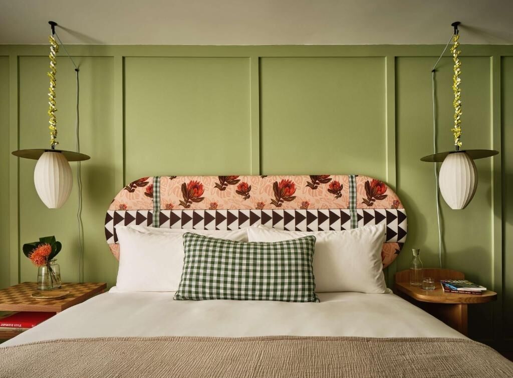 Ein Zimmer mit einem Bett, zwei Nachttischen, einem karierten Kopfkissen und einem blumengemusterten Kopfteil.