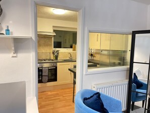 A compact kitchen with a gas stove, oven, and a window with curtains. - Sapphire 1BR House Pet Friendly NR Addenbrookes (Cambridge)