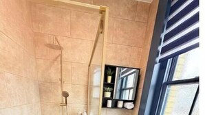 A modern bathroom with a glass shower enclosure, a sink, and a window. - Apartment 1
Modern, Cozy Apartment in a Prime Central Location (Norwich)