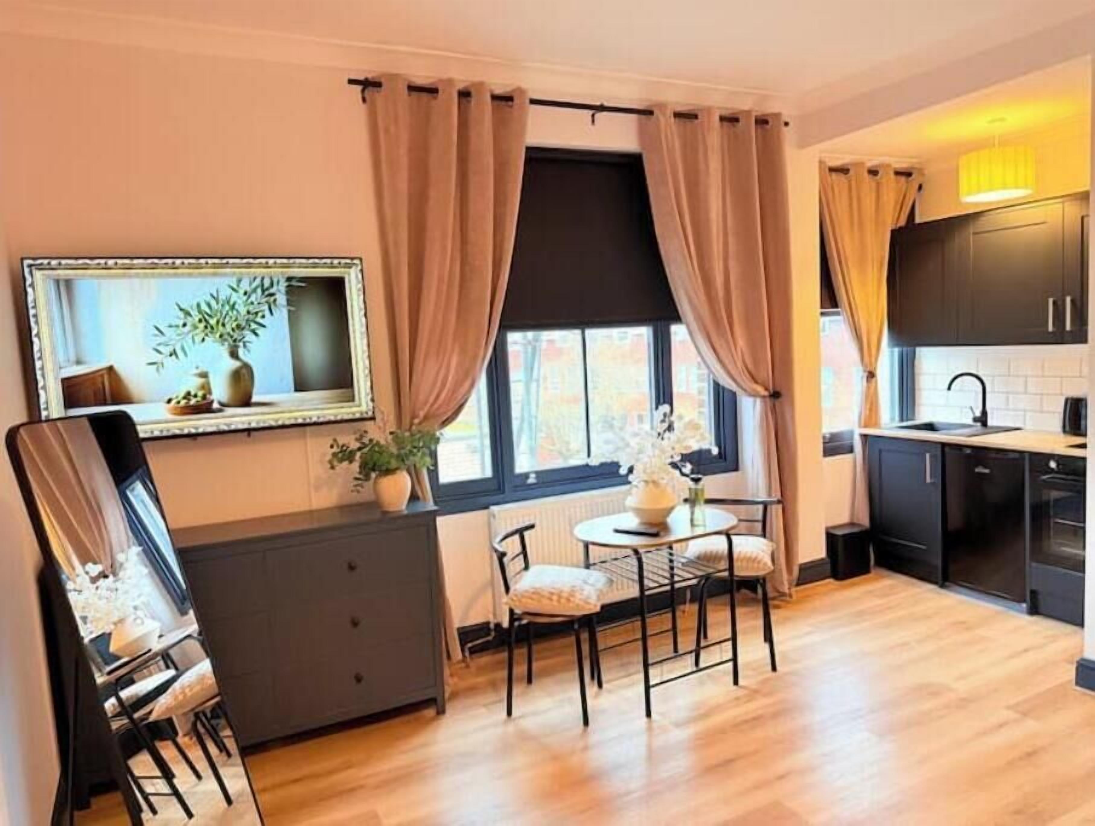 Une cuisine compacte avec un coin repas, un grand miroir et une fenêtre avec des rideaux.