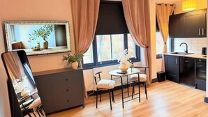 A compact kitchen with a dining area, a large mirror, and a window with curtains. - Apartment 1
Modern, Cozy Apartment in a Prime Central Location (Norwich)
