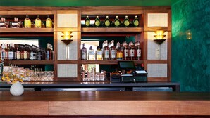 Een bar met flessenrekken vol drank, een kassa en een vaas met bloemen op de toonbank.