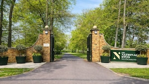 A gated entrance to The National Stud, part of The Jockey Club, with brick walls and potted plants. - Amber 1BR Apart 14 min Walk to Tattersalls (Newmarket)