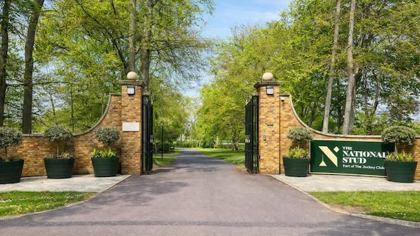 A gated entrance to The National Stud, part of The Jockey Club, with brick walls and potted plants. - Amber 1BR Apart 14 min Walk to Tattersalls (Newmarket)
