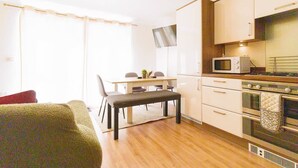Un angolo cottura funzionale, dotato di forno a microonde, forno e una zona pranzo con tavolo e sedie.
