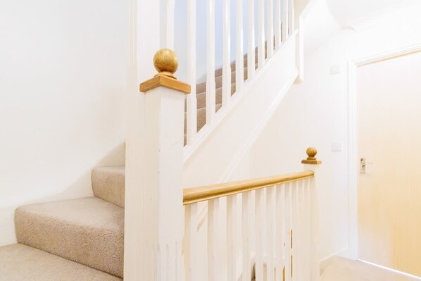 A staircase with beige carpeted steps, white railings, and wooden balusters.