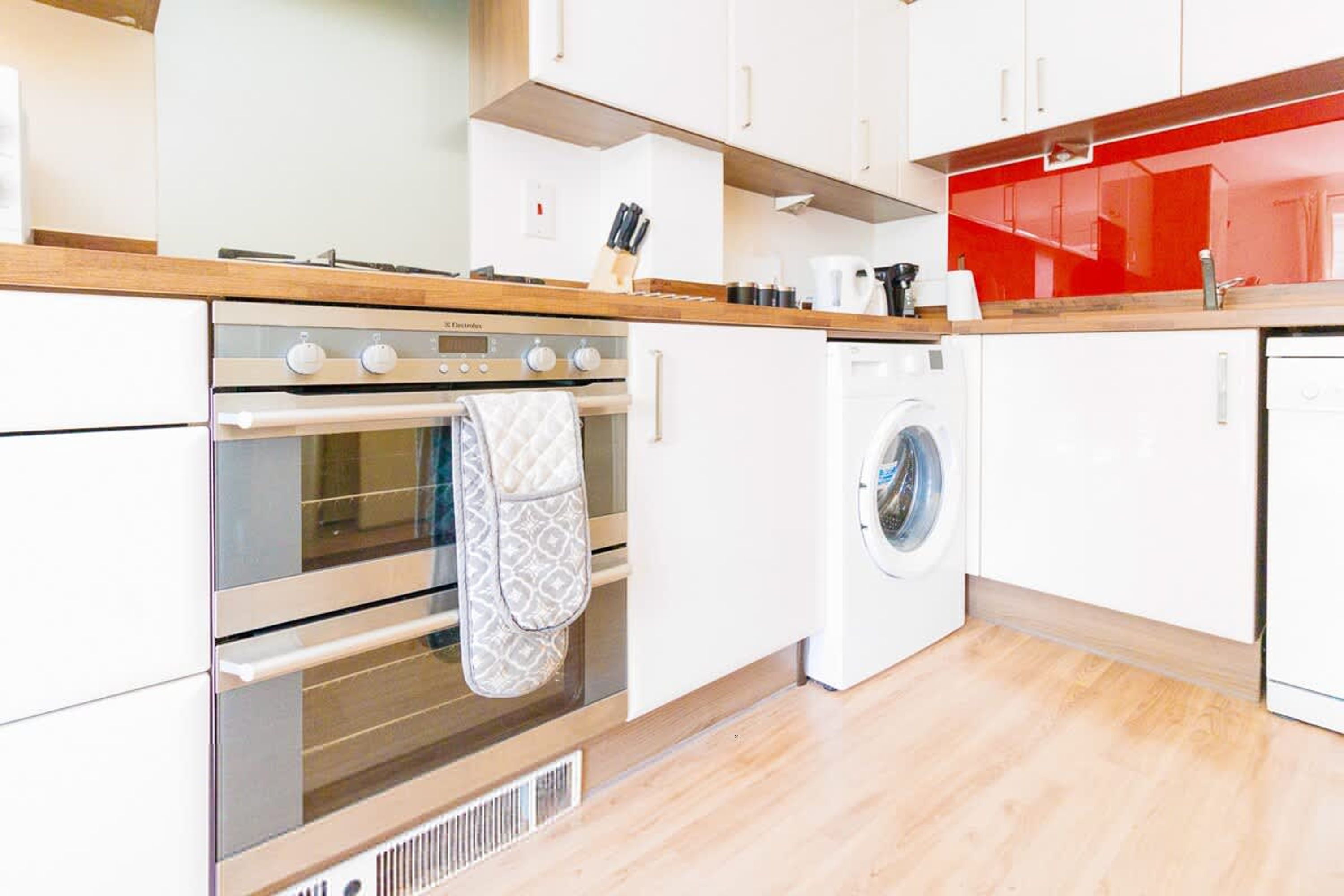 Una cocina moderna con horno integrado, lavadora y encimeras de madera.