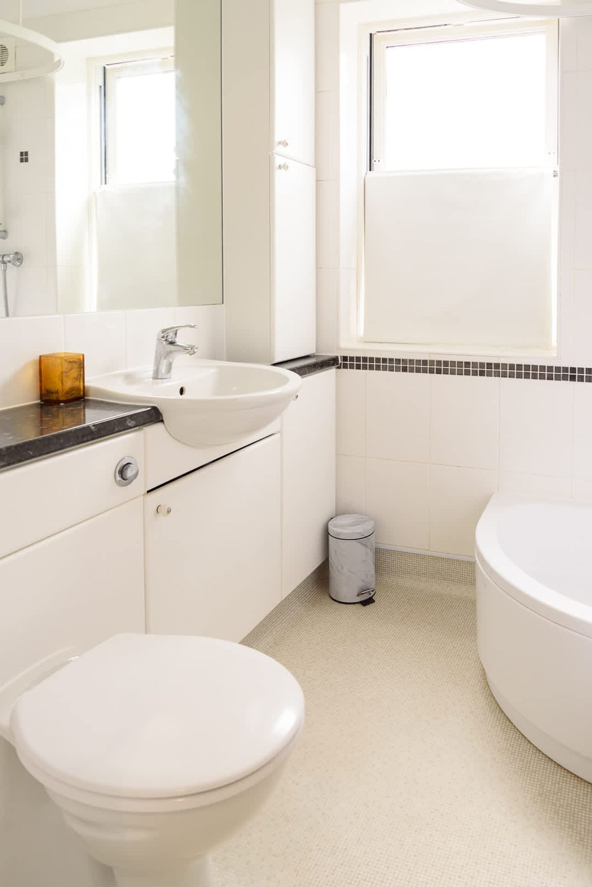 A bathroom with a white sink, a toilet, a mirror, and a window.