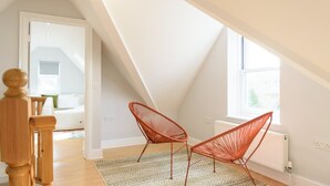 A room with a sloped ceiling, a wooden staircase, and two red wire-framed chairs. - Riverside GEM 6BR With River View NR City Centre (Cambridge)