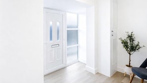A bright, modern interior with a wooden floor, a white door, and a plant in a white pot. - Dettori 2BR With Garden 11 Mins Walk to Gallops (Newmarket)