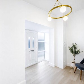 A bright, modern interior with a wooden floor, a white door, and a plant in a white pot. - Dettori 2BR With Garden 11 Mins Walk to Gallops (Newmarket)