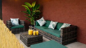 A cozy outdoor seating area with wicker furniture, a green sofa, and a large plant. - Dettori 2BR With Garden 11 Mins Walk to Gallops (Newmarket)