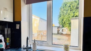 A kitchen with a sink, a window, and a view of a patio with outdoor furniture. - 4 BR House 13 min Walk to Tattersalls Private Garden Parking (Newmarket)