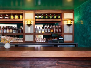 Een bar met flessenrekken vol drank, een kassa en een vaas met bloemen op de toonbank.