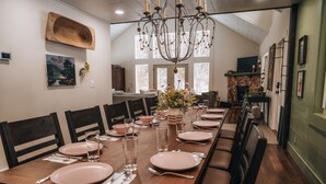 A dining room with a long wooden table set for six, surrounded by dark wooden chairs.