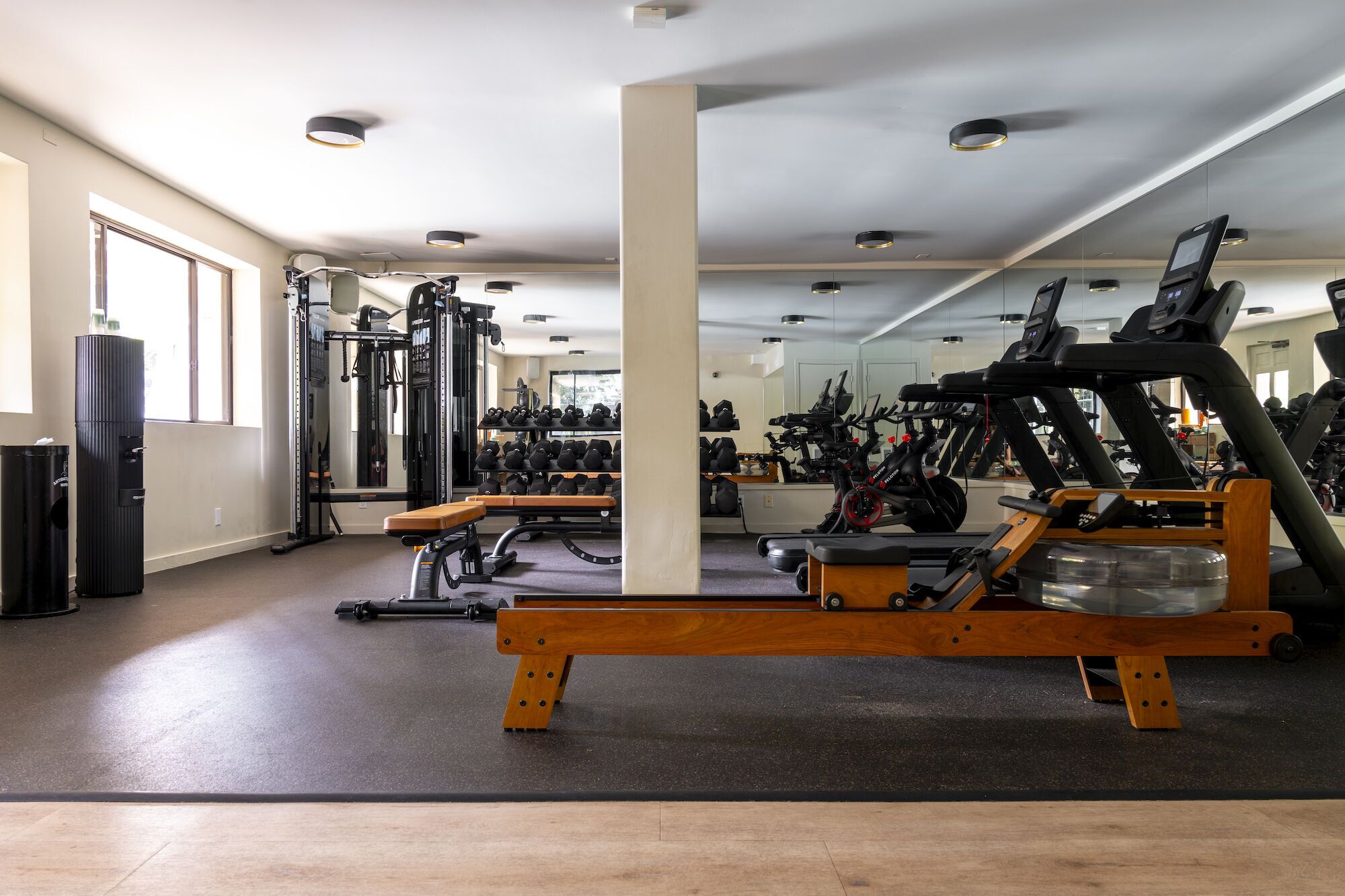 A gym with exercise equipment, a bench, and a mirrored wall.