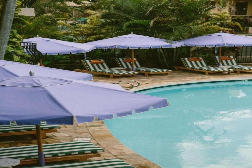 A pool area with lounge chairs and umbrellas, surrounded by greenery.