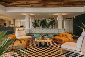 A lobby with checkered flooring, a reception desk, seating areas, and a large plant. - Wayfinder Waikiki | Corner King Lanai | Design Hotel, Saltwater Pool (Honolulu County)