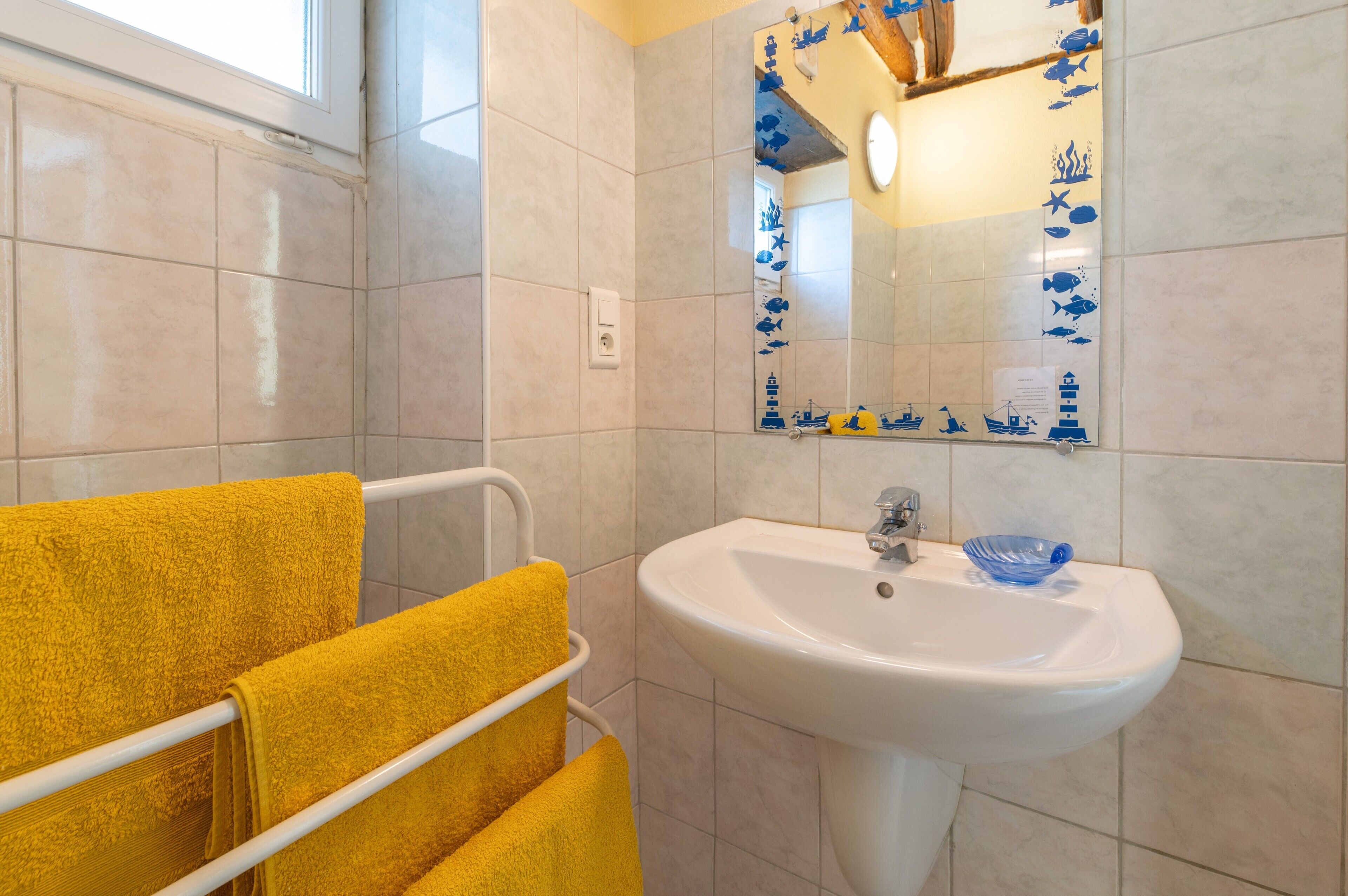 Une salle de bain avec un lavabo, un miroir et des serviettes jaunes.