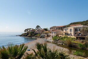 A coastal residential area with houses along the beach, a small stream, and clear skies. - Apartment 'Maisonnette Chez Aurèle' with Mountain View (Santa-Maria-di-Lota)