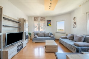 A modern living room with a flat-screen TV, two sofas, a coffee table, and a window with a view. - Stylish Apartment in Fellbach with Balcony and Wi-Fi (Fellbach)