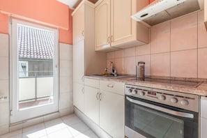 A kitchen with white cabinets, a stainless steel oven, and a tiled backsplash. - Stylish Apartment in Fellbach with Balcony and Wi-Fi (Fellbach)
