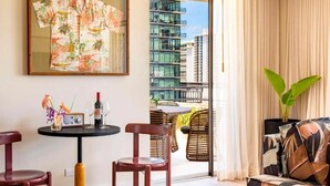 Une chambre d’hôtel avec un balcon, une table avec des chaises, un canapé et un tableau au mur.