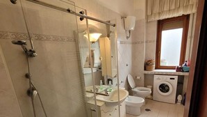 A bathroom with a glass-enclosed shower, a toilet, a sink, and a washing machine. - Lilly's house (Avellino)