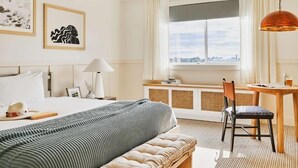 Ein Hotelzimmer mit Bett, Schreibtisch, Stuhl, Lampe und Bildern an den Wänden.