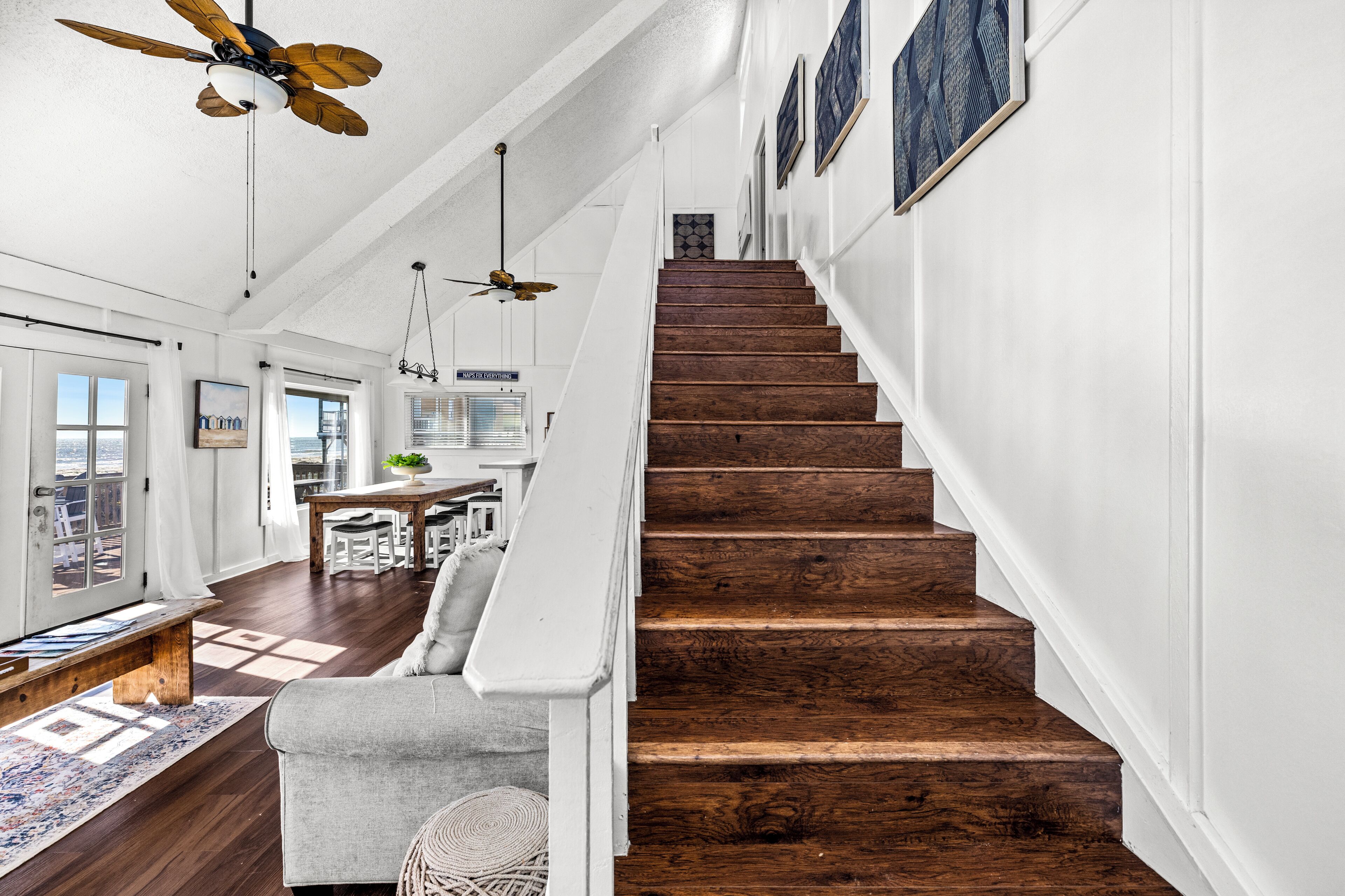 A staircase with wooden steps and white walls, leading to a dining area with a table and chairs.