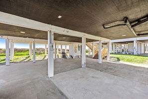 Un espace intérieur abrité, doté d’un sol en béton, de piliers blancs et d’un ventilateur de plafond.