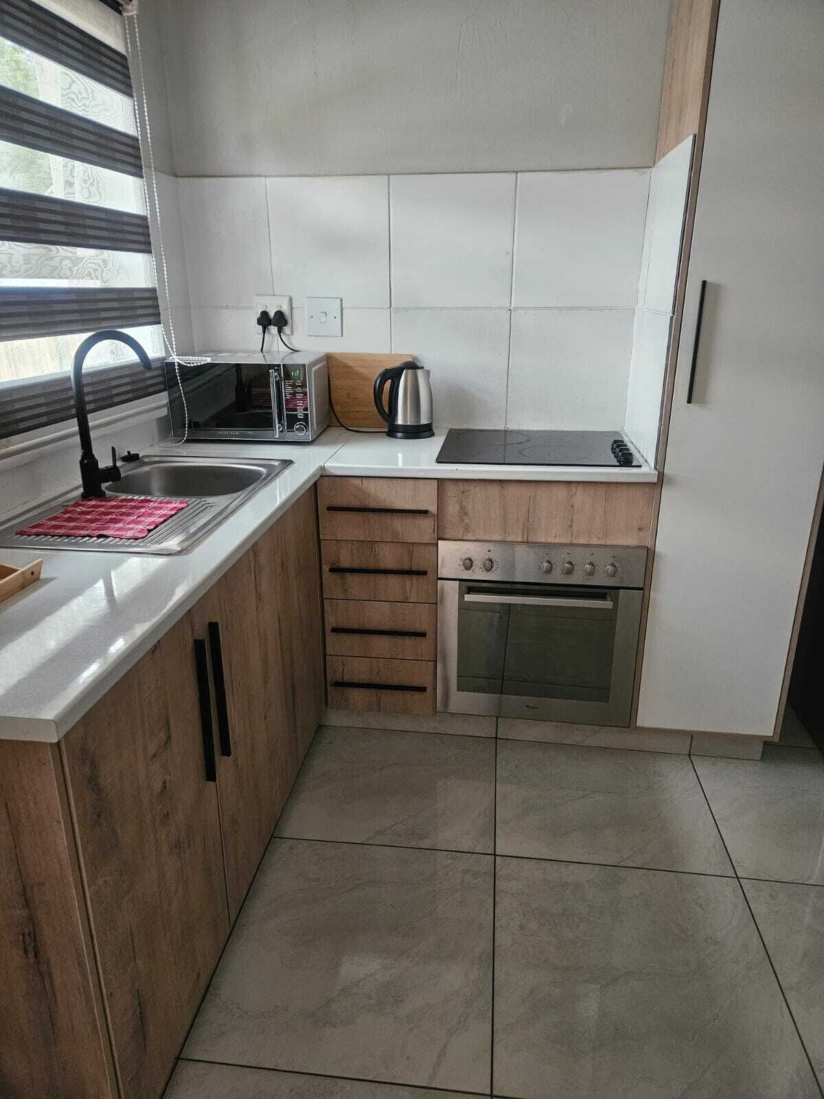 A compact kitchen with a sink, a toaster, a kettle, and a stove.