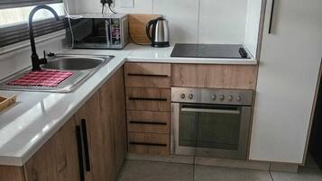 A compact kitchen with a sink, a toaster, a kettle, and a stove.